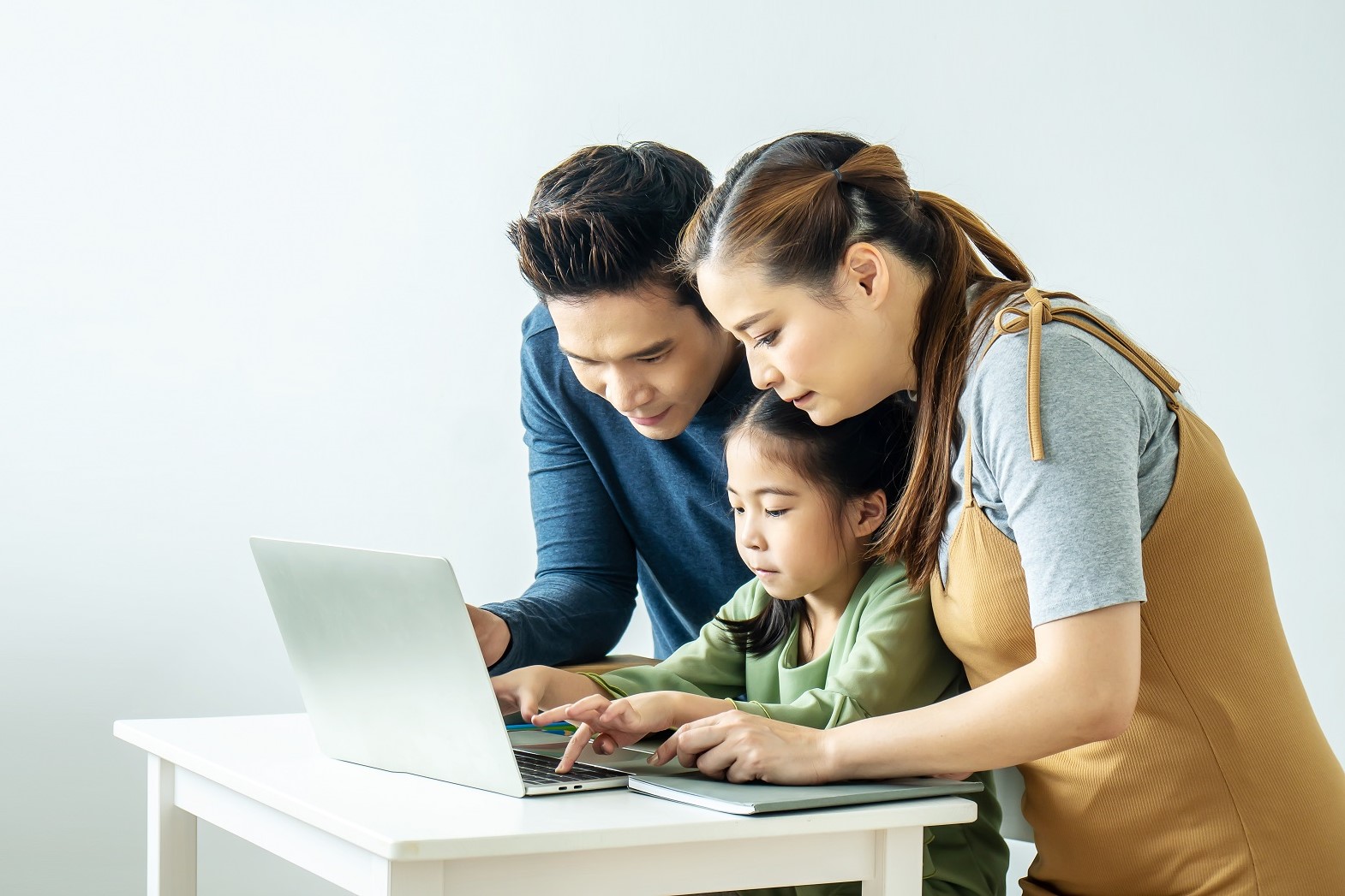 Happy young Asian family using at the laptop to surf internet together at home, , relaxing at home for lifestyle concept