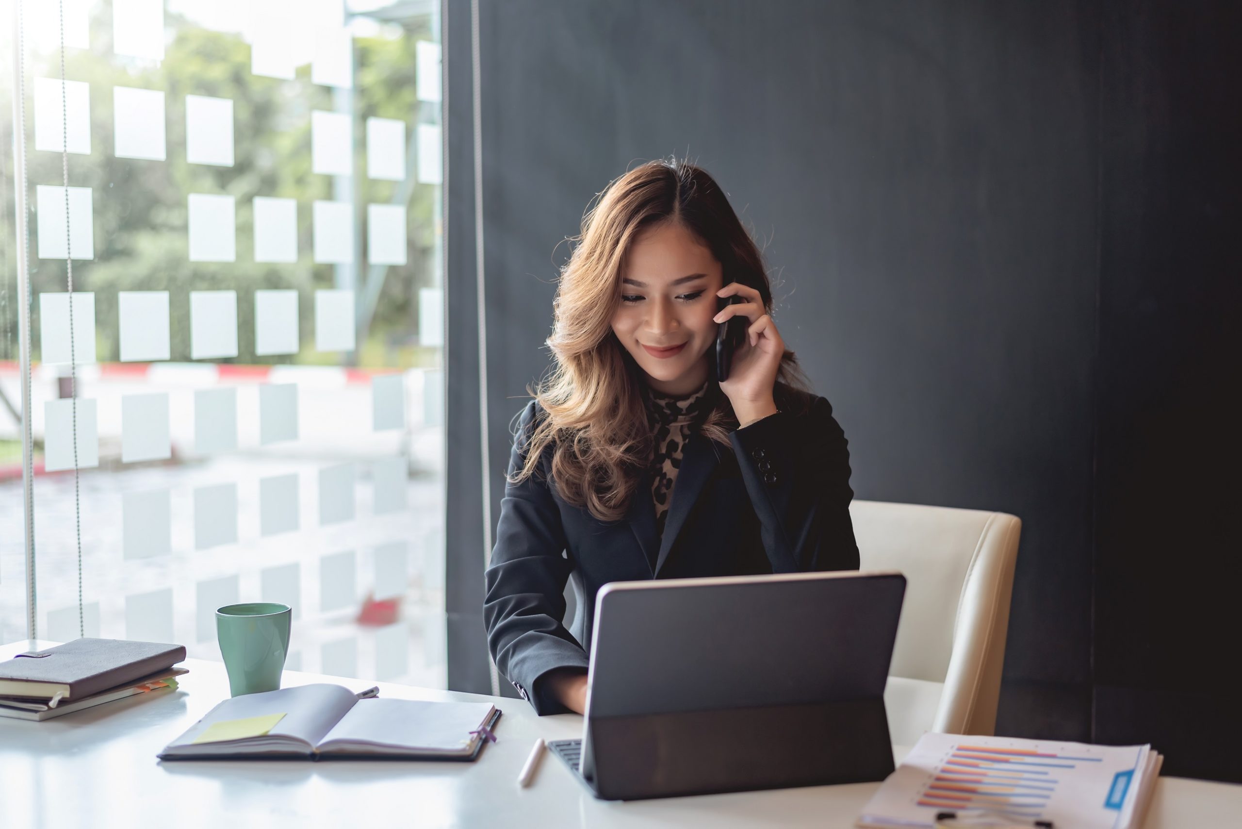 Young asian businesswoman beautiful charming smiling and talking on the mobile phone in the office
