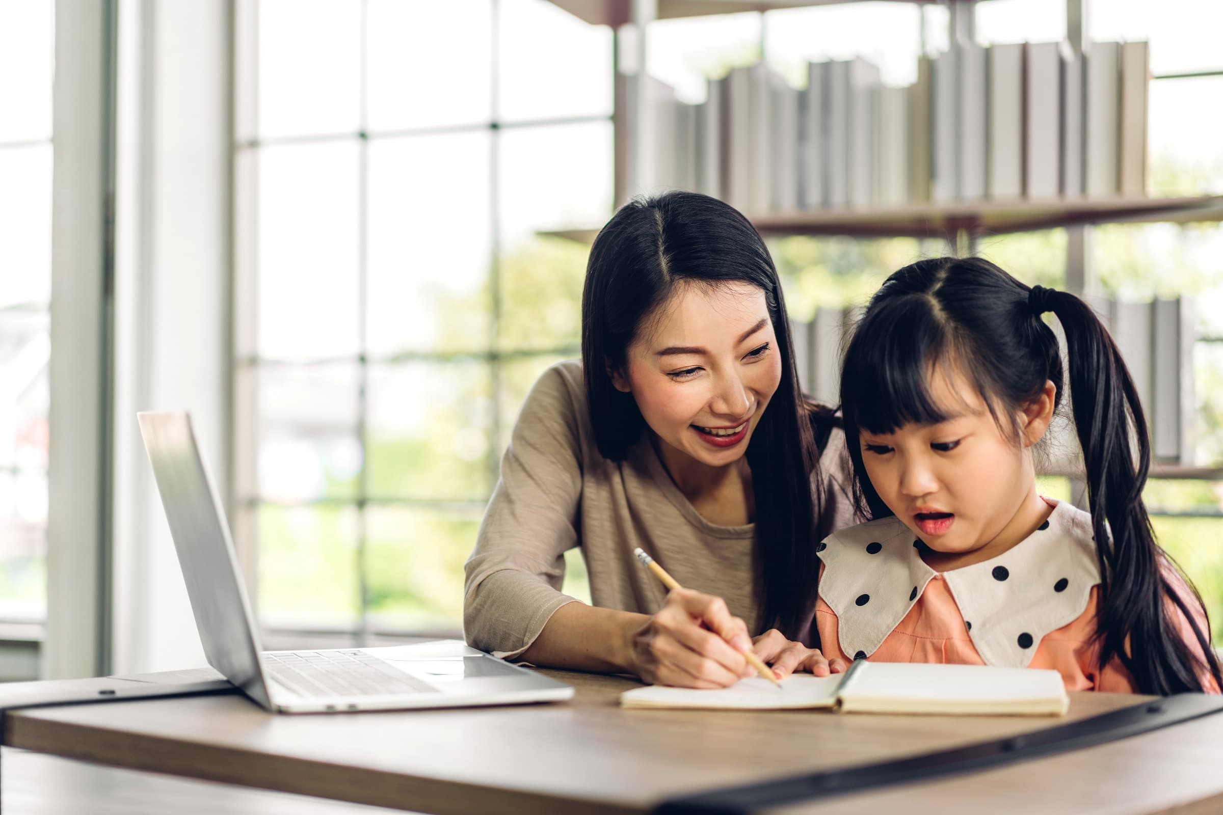 Mother and asian kid little girl learning and looking at laptop computer making homework studying knowledge with online education e-learning system