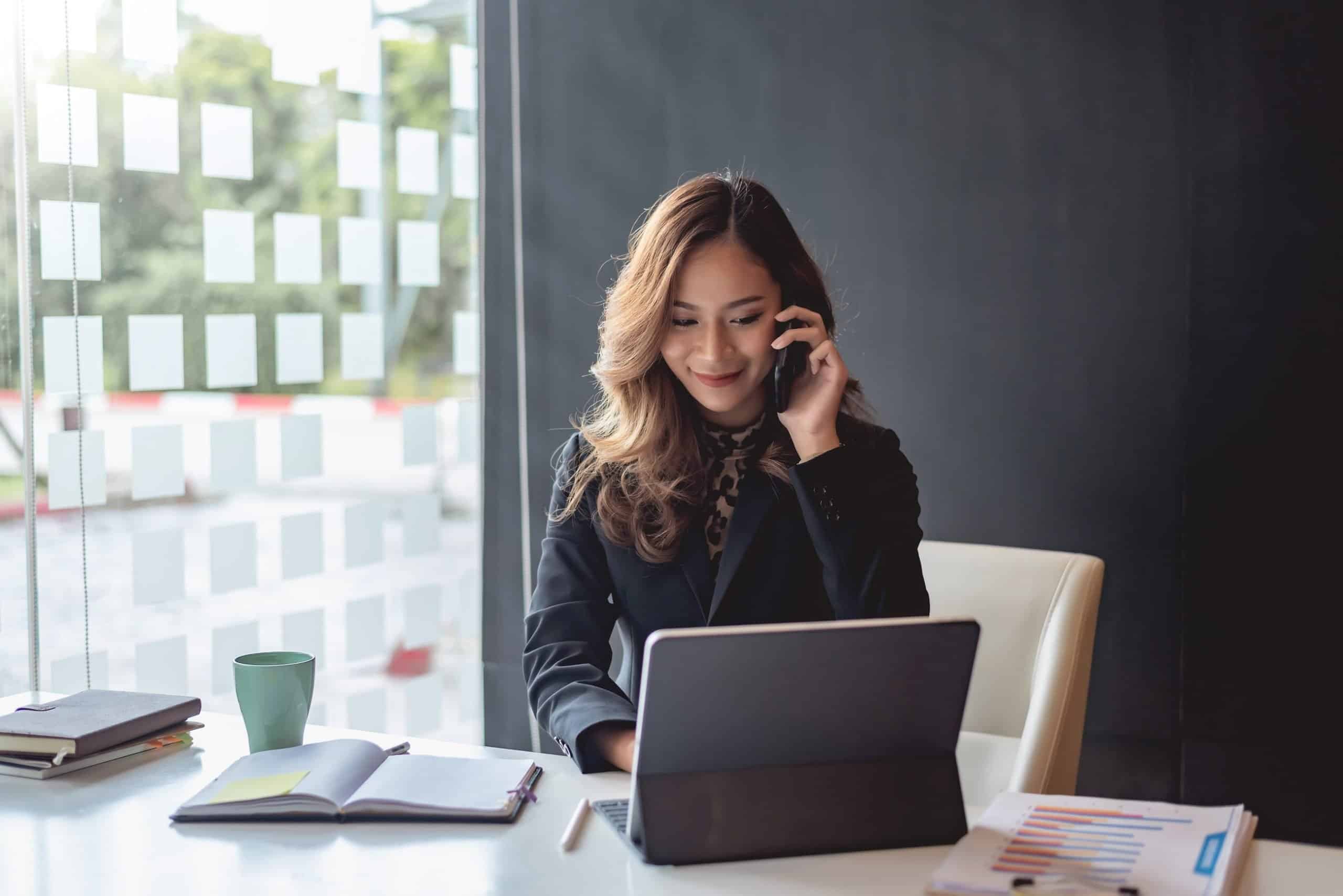 Young asian businesswoman beautiful charming smiling and talking on the mobile phone in the office