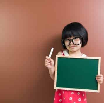 Asian school kid with chalk and chalkboard