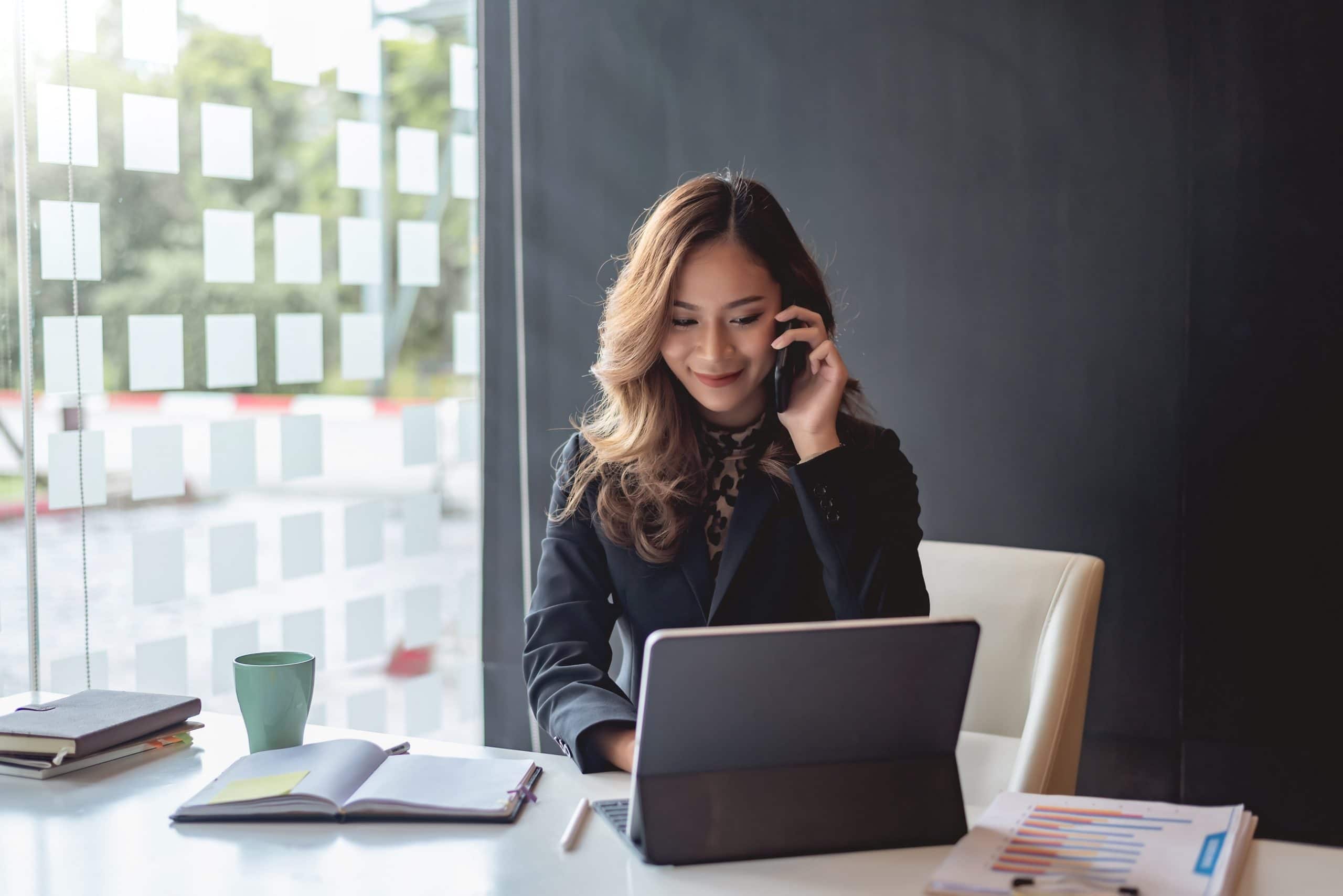 Young asian businesswoman beautiful charming smiling and talking on the mobile phone in the office